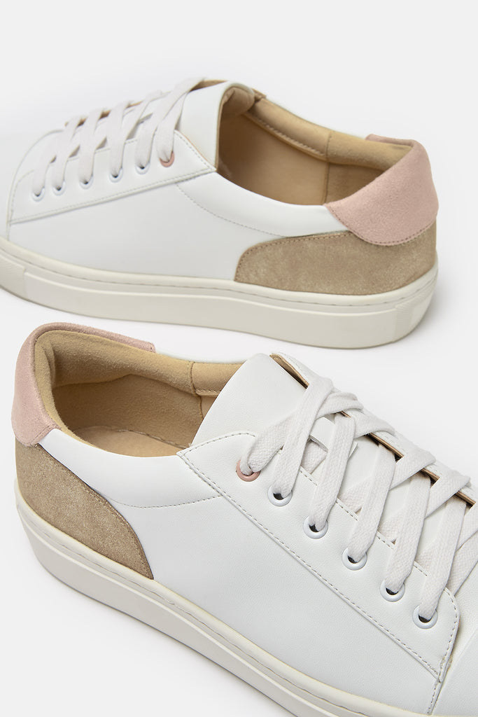 close up detail of white vegan leather trainers, showing gold and pink heel detail