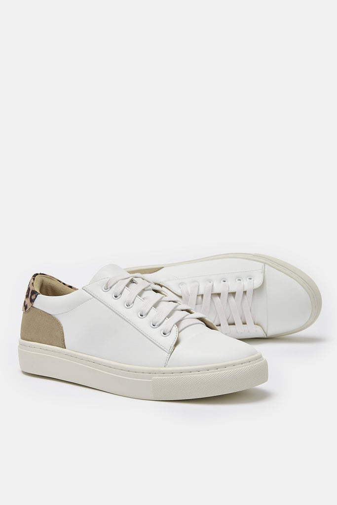 Pair of white vegan leather trainers with gold and leopard heel detail- one trainer is shown lying on its side