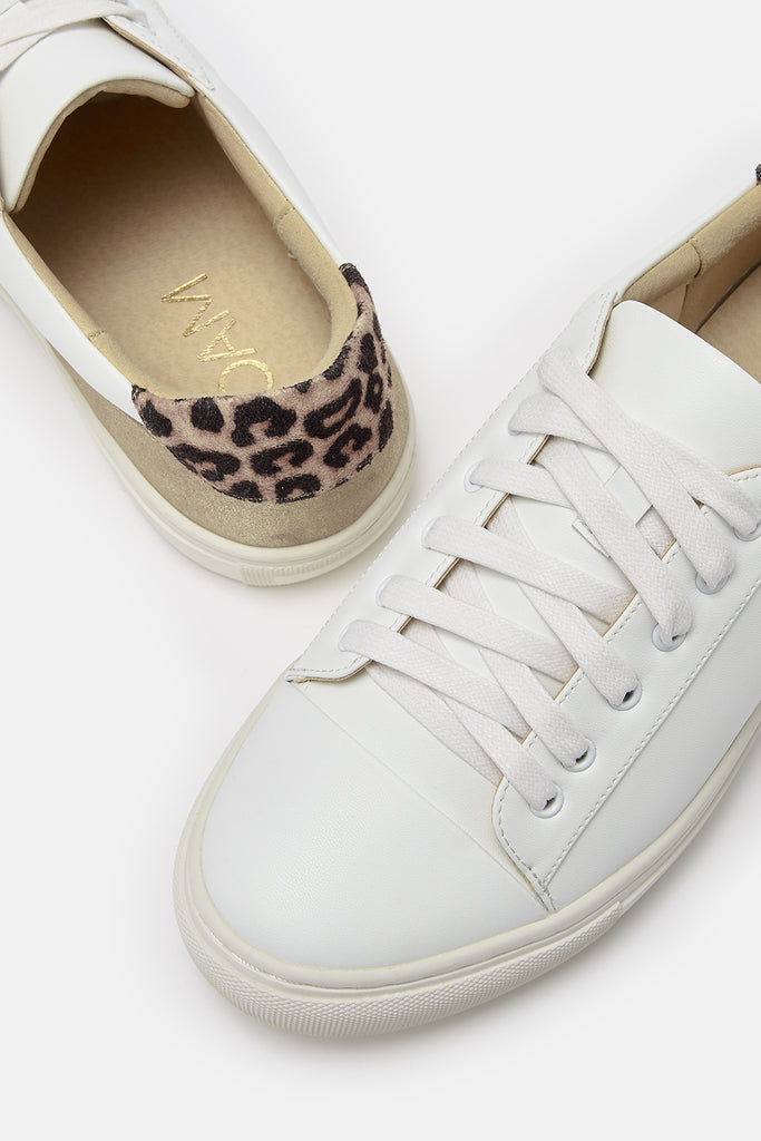 Close up detail of a pair of white vegan leather trainers showing gold and leopard heel detail