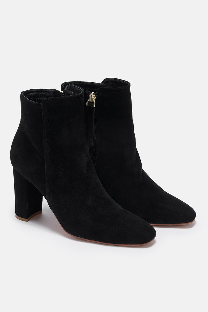 Black suede ankle boots on a white background