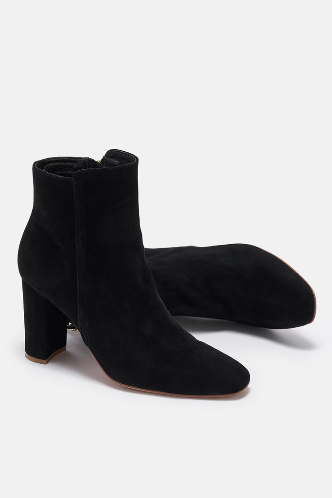 Black suede ankle boots on a white background