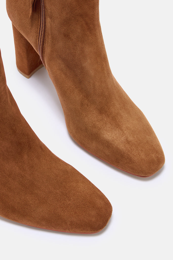 Brown suede ankle boots on a white background