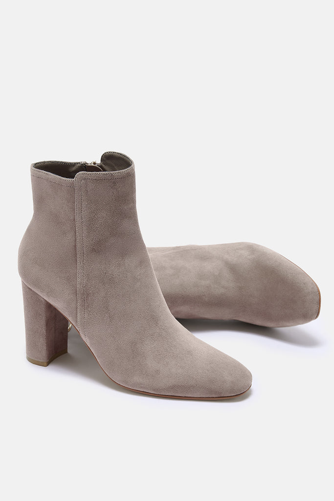 Pair of taupe suede ankle boots on a white background