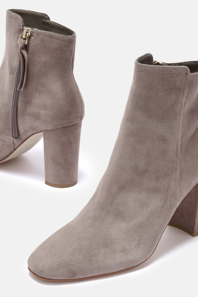 Pair of taupe suede ankle boots with block heels on a white background