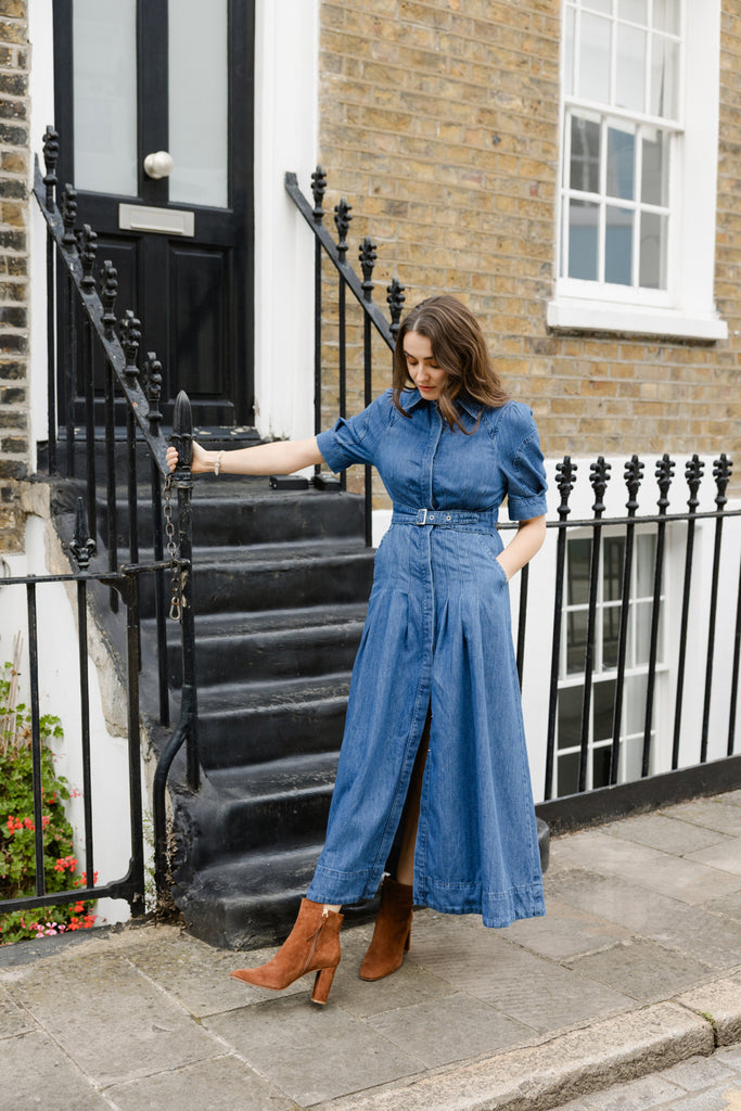 Woman in a blue denim outfit with brown ankle boots standing on a staircase in an urban setting
