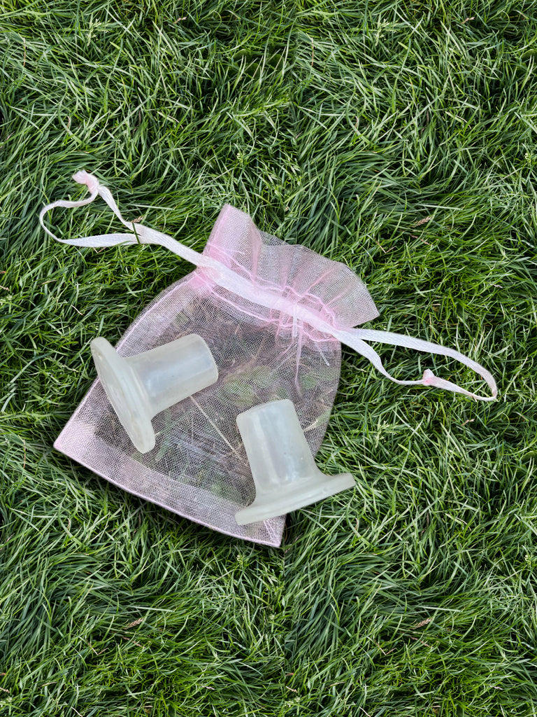 Clear silicone heel protectors in a pink drawstring bag on grass