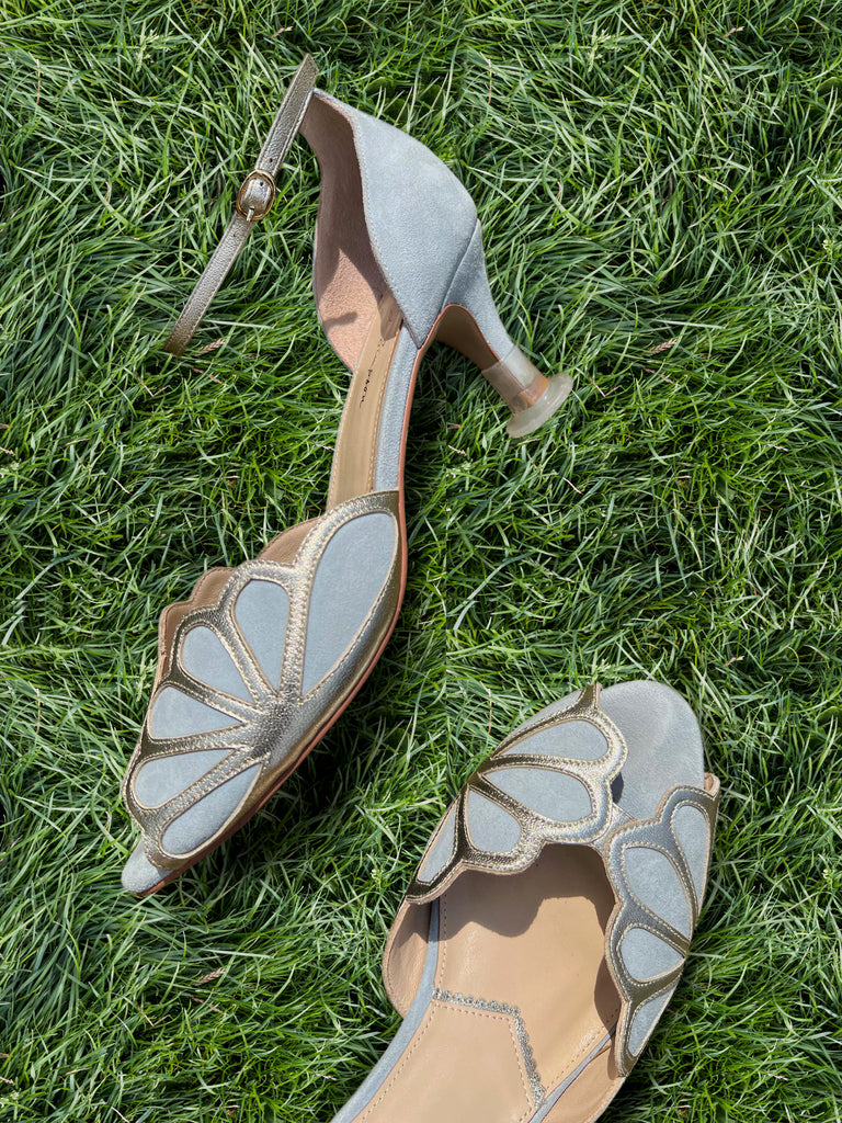 Pair of high-heeled shoes with butterfly design on grass