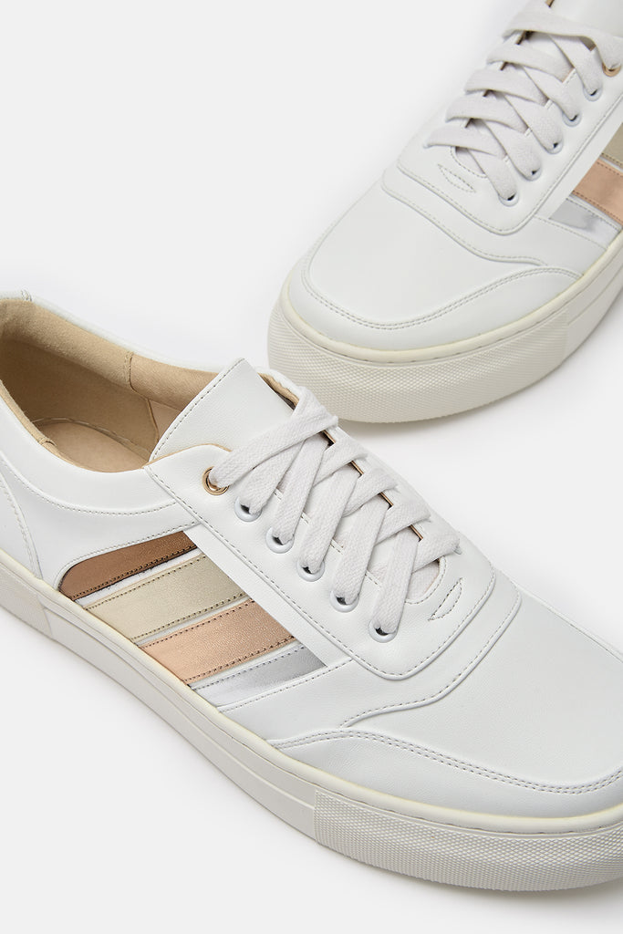 Close up shot of a pair of white vegan leather trainers, showing side stripes in bronze, gold, rose gold and silver.