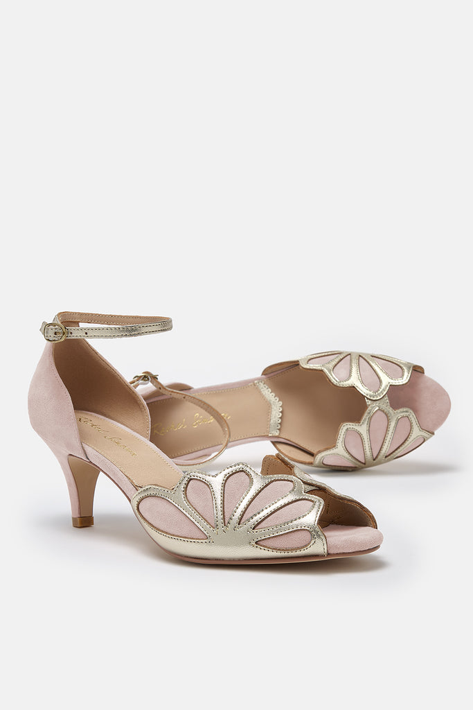 pair of blush pink suede and gold art deco vintage style shoes, with low heels and ankle strap. One of the shoes is lying on its side