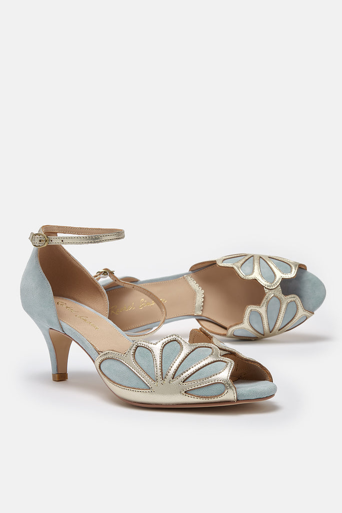 pair of dusky blue suede and gold art deco vintage style shoes, with low heels and ankle strap. One of the shoes is lying on its side
