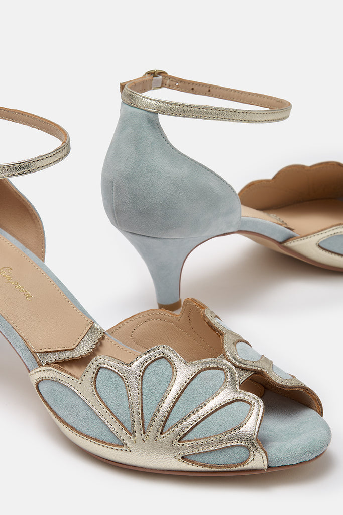 close up detail shot of a pair of dusky blue suede and gold art deco vintage style shoes, with low heels and ankle strap
