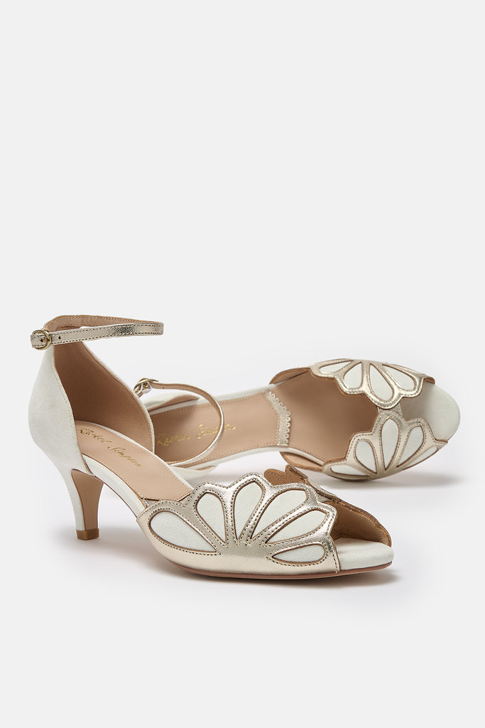 pair of ivory suede and gold art deco vintage style wedding shoes, with low heels and ankle strap- one shoe is lying on its side