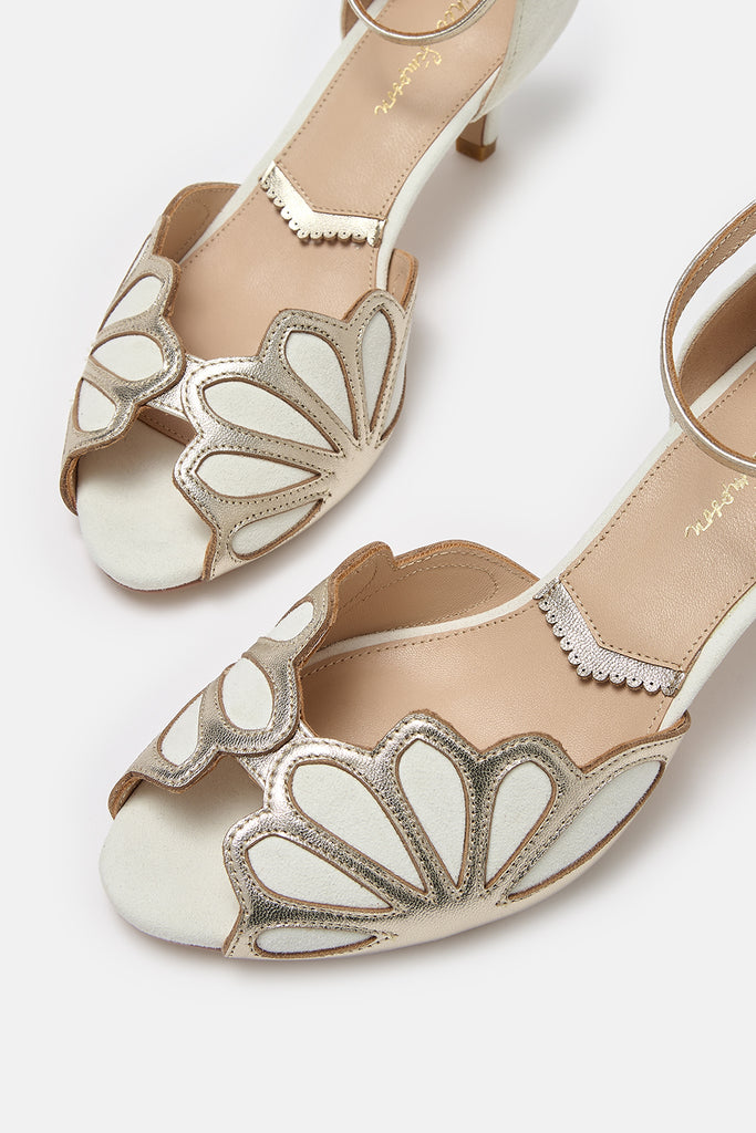 close up detail shot of a pair of ivory suede and gold art deco vintage style wedding shoes, with low heels and ankle strap