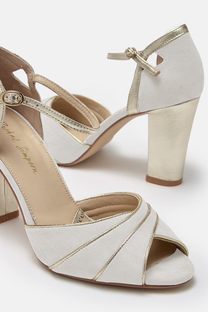 close up detail shot of a pair of ivory suede wedding shoes with gold block heel and ankle strap