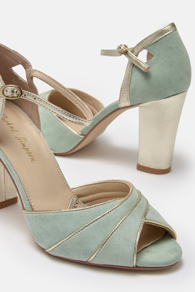 close up detail shot of a pair of mint green suede occasion shoes with gold block heel and ankle strap