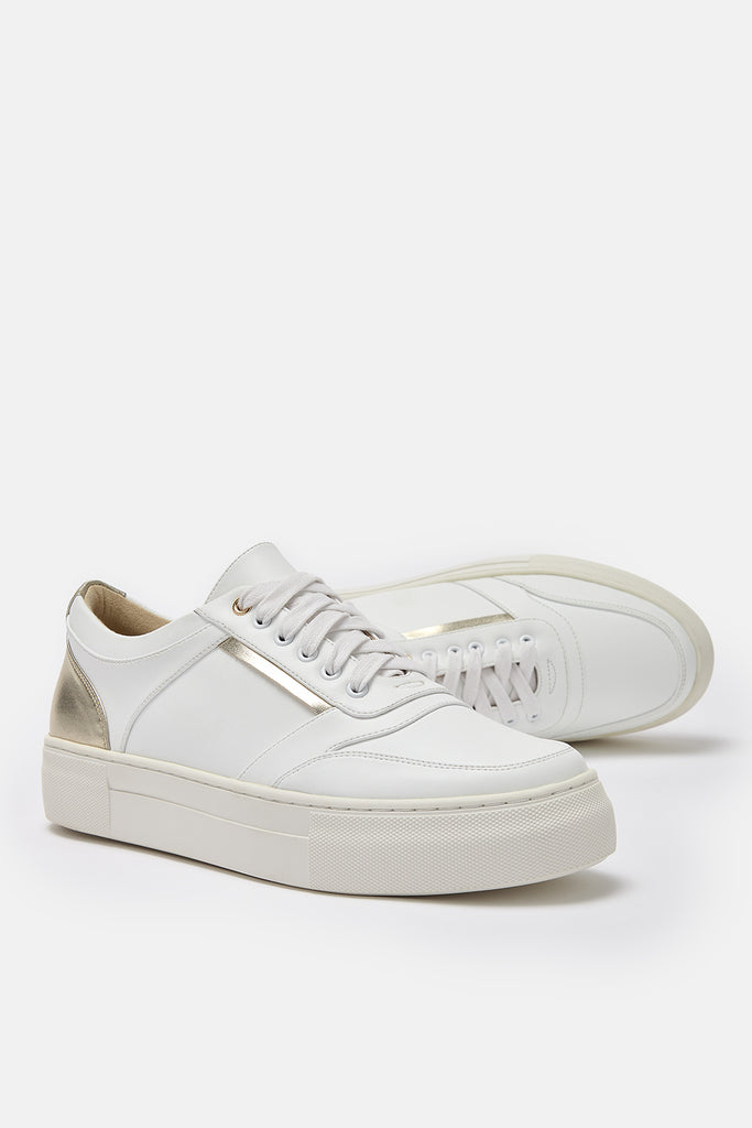 Pair of white and gold vegan leather trainers- one trainer is shown lying on its side.