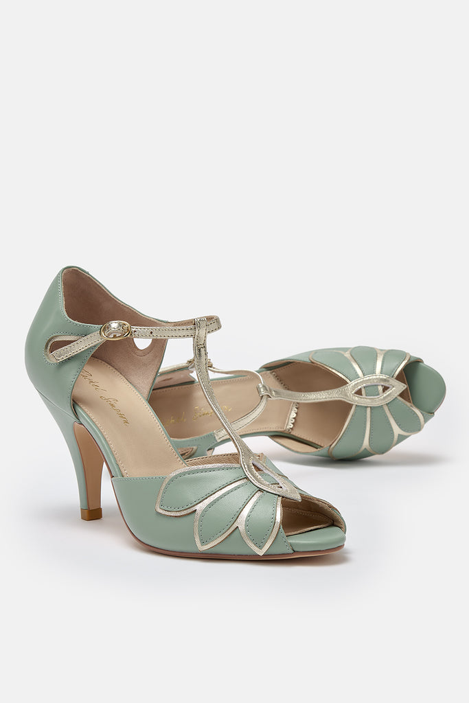 a pair of mint green and gold leather t-bar occasion shoes with mid heels and ankle strap