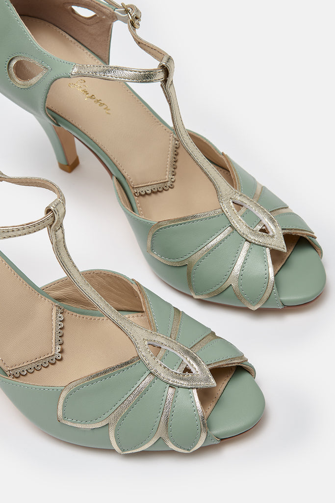close up detail shot of a pair of mint green and gold leather t-bar occasion shoes with mid heels and ankle strap