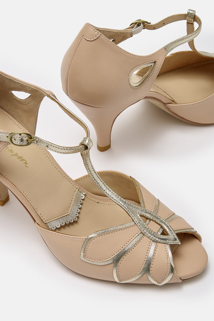 close up detail shot of a pair of blush pink nude and gold leather t-bar occasion shoes with mid heels and ankle strap