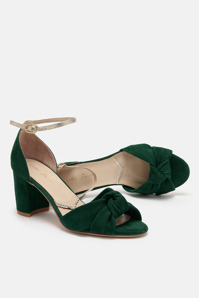 pair of forest green suede block heel shoes with knot detail and gold leather ankle straps- one shoe is lying on its side