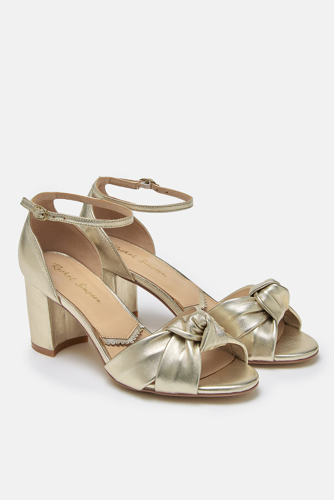 a pair of gold leather block heel occasion shoes with knot detail and ankle straps
