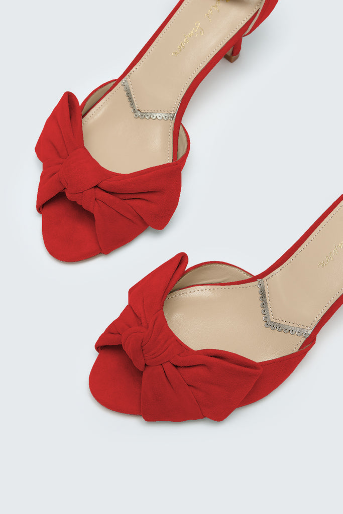 Red shoes with bow details on a white background