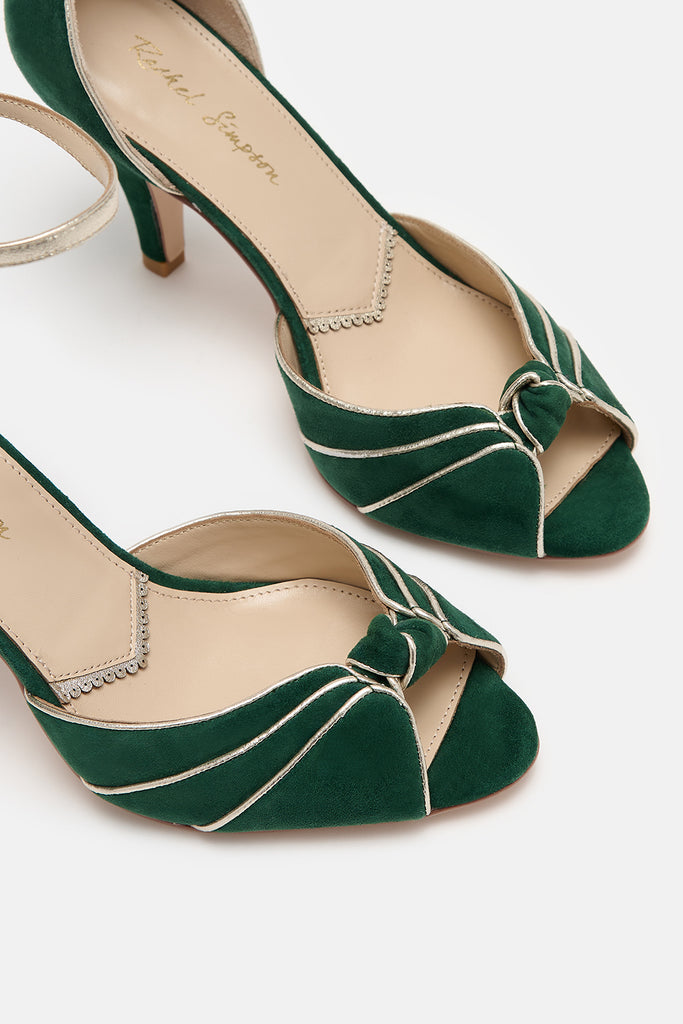 close up detail shot of a pair of forest green and gold two part occasion shoes, with vintage inspired knot detail, mid heels and gold leather ankle straps