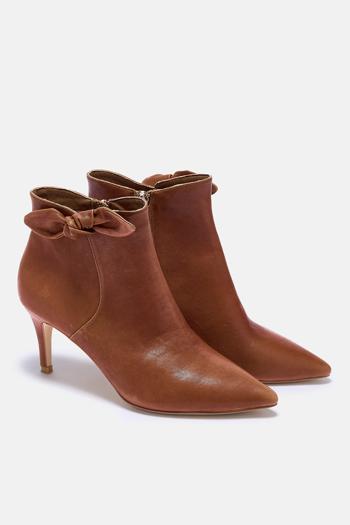 Pair of brown ankle boots with bow details on a white background