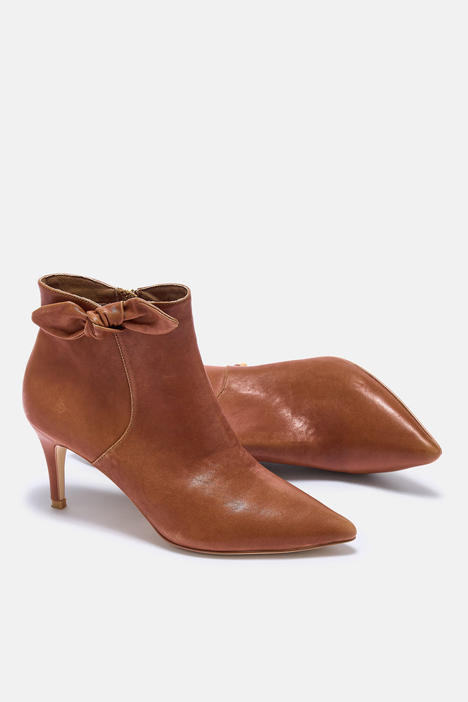 Pair of brown leather ankle boots with bow details on a white background