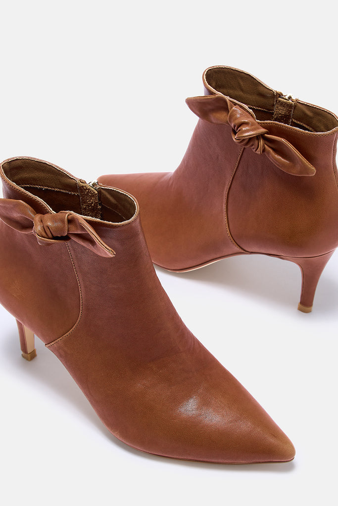 Pair of brown leather ankle boots with bow details on a white background