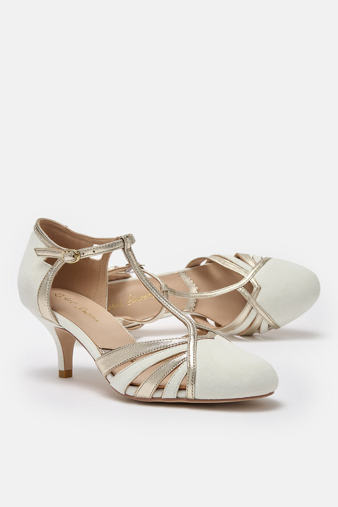 pair of ivory suede and gold leather twenties vintage style t-bar wedding shoes, with low heels and ankle straps- one shoe is lying on its side