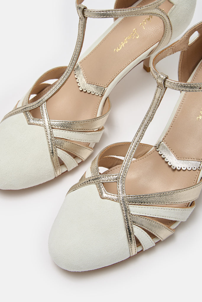 close up detail shot of a pair of ivory suede and gold leather twenties vintage style t-bar wedding shoes, with low heels and ankle straps