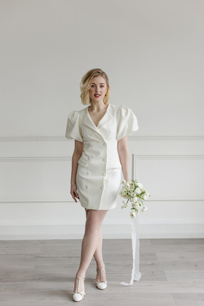 bride in a short ivory dress, holding a bouquet of cream flowers, wearing a pair of ivory suede and gold leather twenties vintage style t-bar wedding shoes, with low heels and ankle straps
