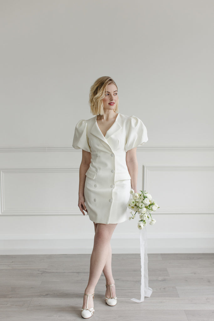 bride in a short ivory dress holding a bouquet of cream flowers, wearing a pair of ivory suede and gold leather twenties vintage style t-bar wedding shoes, with low heels and ankle straps