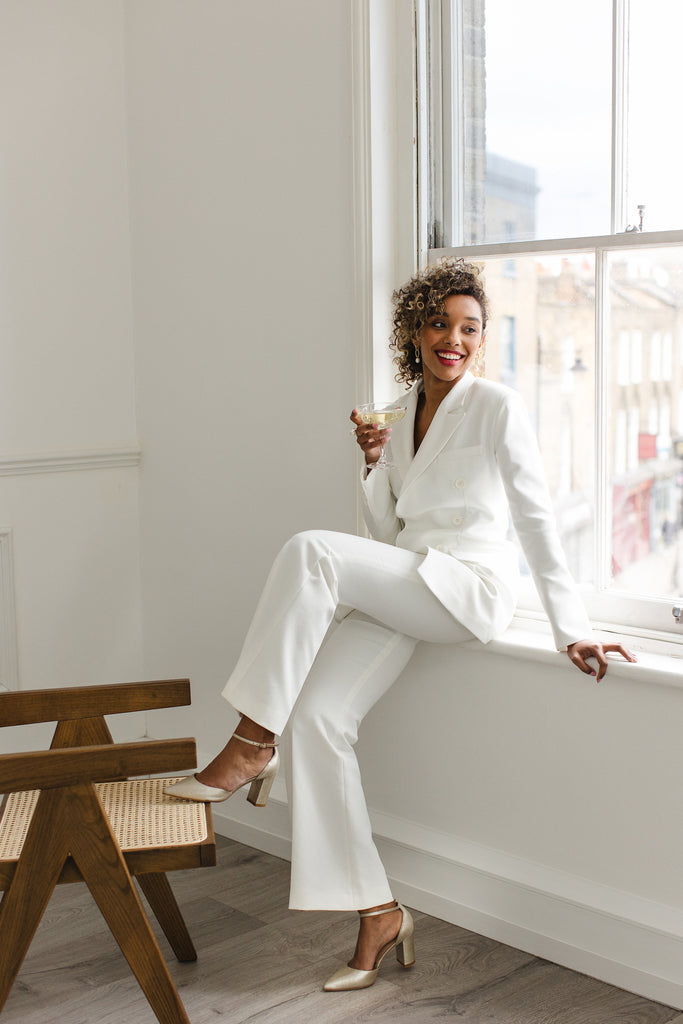 bride in an ivory trouser suit, drinking a glass of champagne wearing pair of antique gold leather two part pointed wedding shoes with block heels and ankle straps